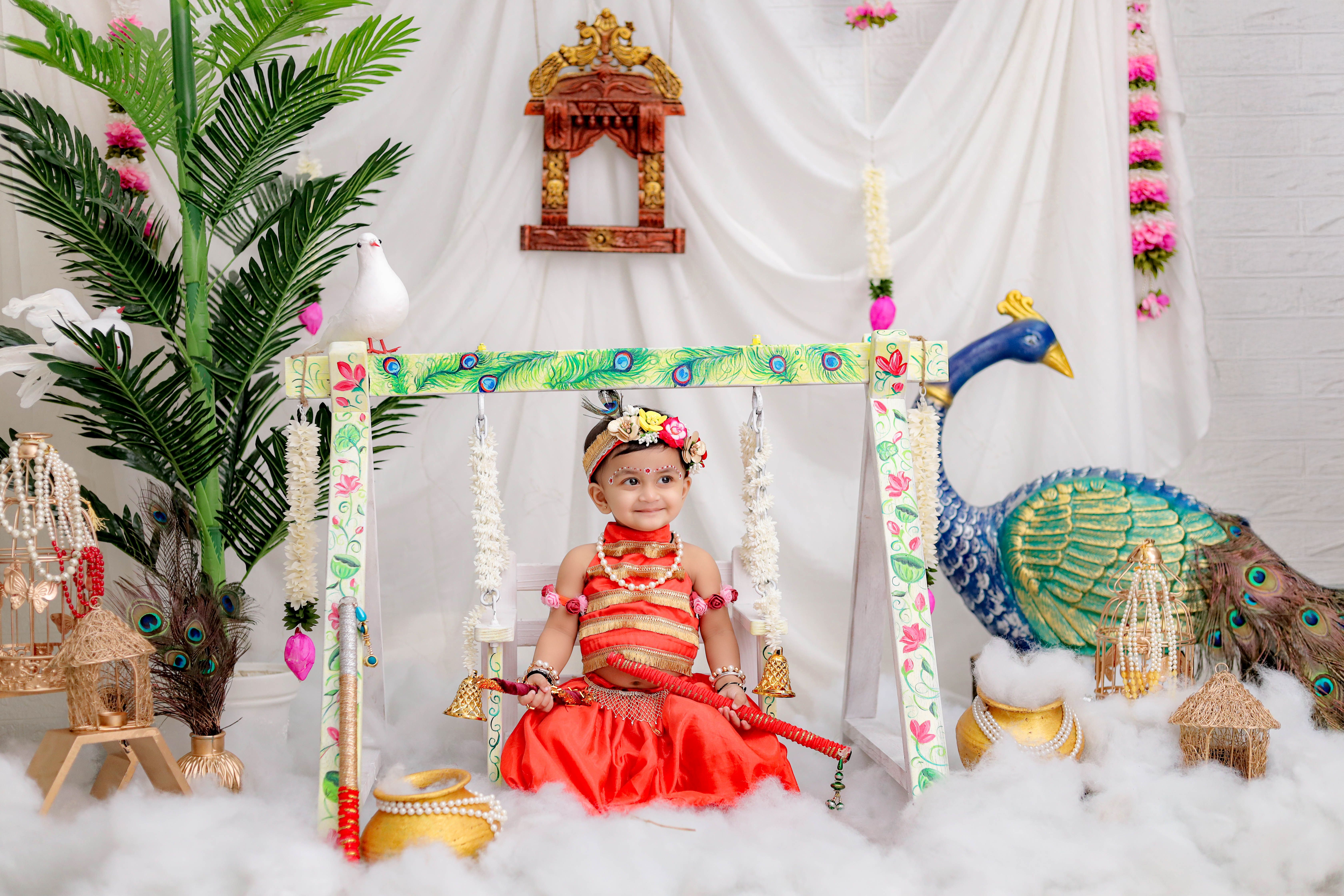Wooden Indian cradle draped with marigolds and brass bells for a namkaran ceremony